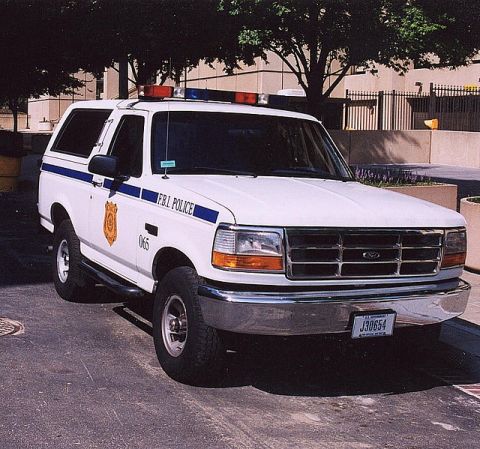 1994 Ford Bronco - This white Ford Bronco police SUV displays FBI POLICE markings and emergency lights on its roof.