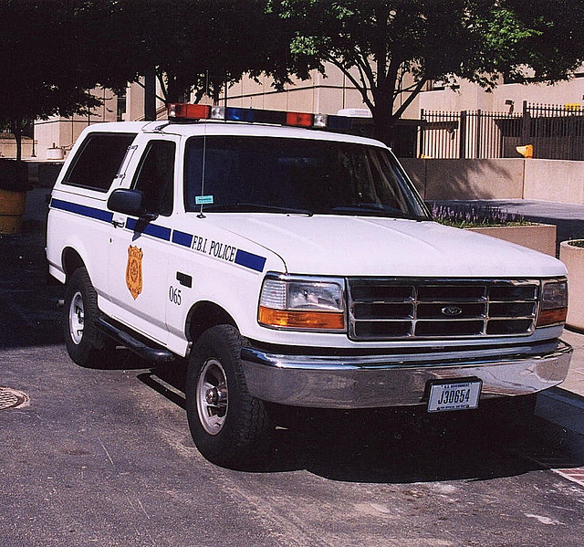 White Ford Bronco police SUV with blue stripe and FBI POLICE text, parked on asphalt