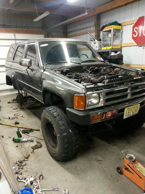 1987 Toyota 4Runner - This 1987 Toyota 4Runner is in a garage, with its hood open and tools scattered around, suggesting it is undergoing maintenance.