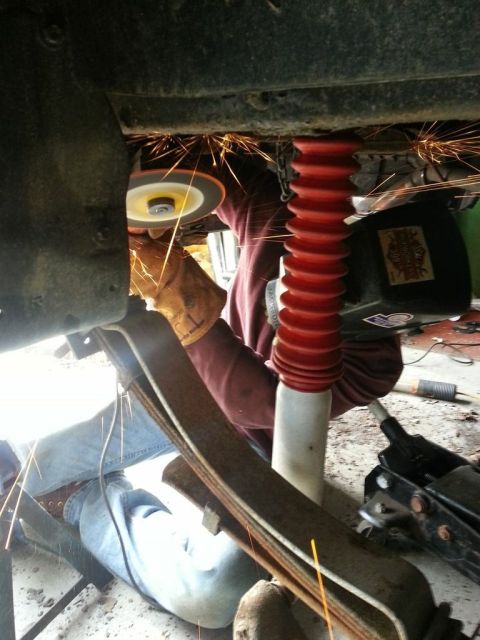 1987 Toyota 4Runner - A person is working on the undercarriage of a vehicle, with sparks flying from a grinder.