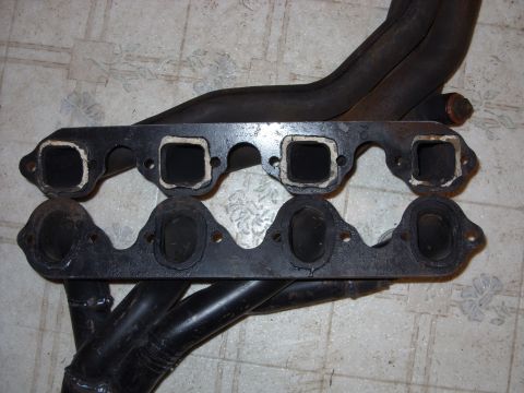 1967 Ford F-250 - Close-up view of two exhaust manifolds, one above the other, on a tiled surface.