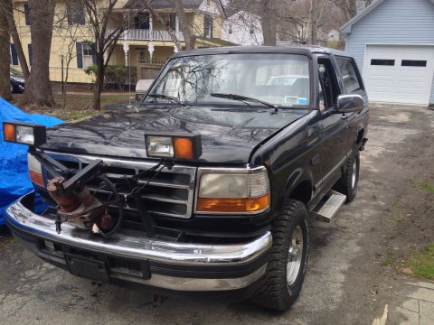 1996 Ford Bronco - This black Ford Bronco is equipped with a plow mount and auxiliary lights, suggesting it's used for snow removal.