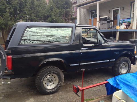 1996 Ford Bronco - This black 1996 Ford Bronco is shown from the side, its spare tire mounted on the rear.