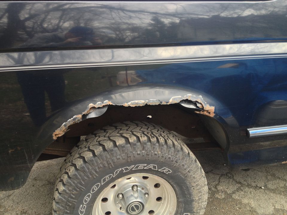 Close-up of rusted rear wheel well on a 1996 Ford Bronco with Goodyear tires