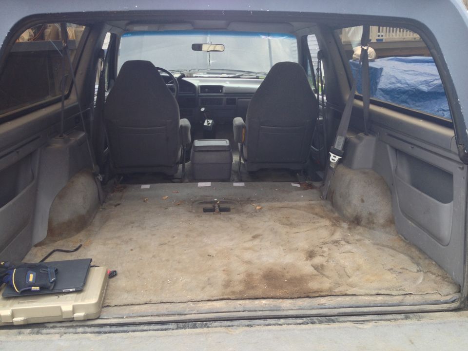 Interior of a 1992 Ford Bronco with worn carpet, two front seats, and a center console