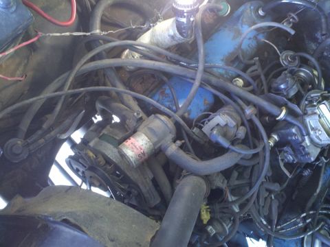 1978 Ford Bronco - A close-up view of a cluttered engine bay, showing various hoses, wires, and mechanical parts.