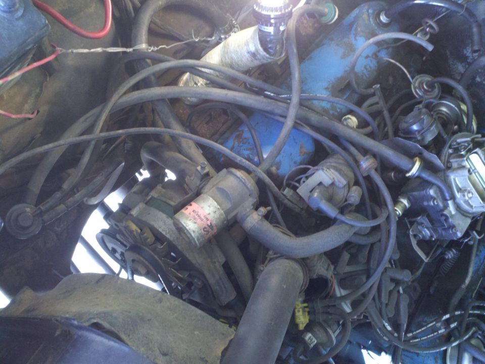 Engine bay with hoses, wires, and engine components visible. A label on a part reads 'SV'