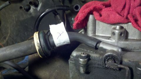 1978 Ford Bronco - Close-up of a carburetor with a hose and a piece of tape marked 'X'.