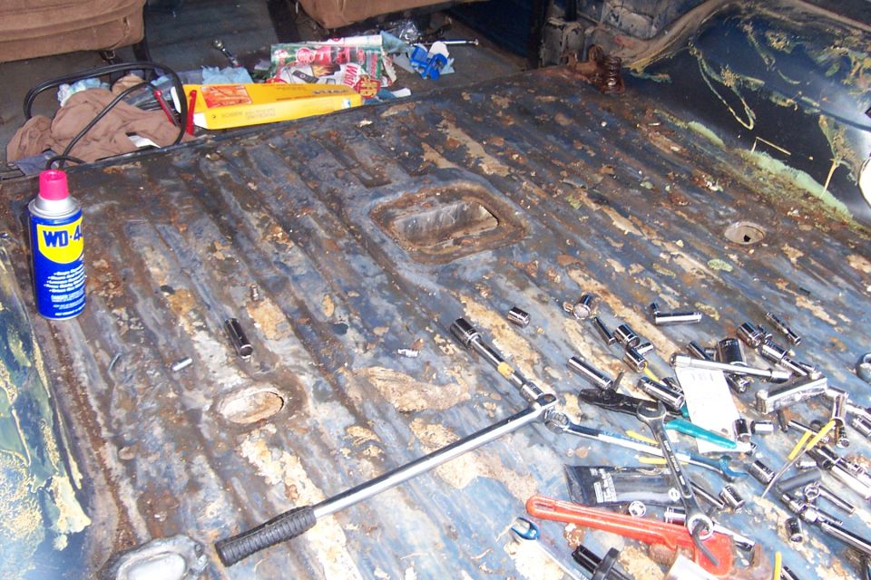 Rusty stripped truck cargo floor covered with sockets, ratchets and a WD-40 can