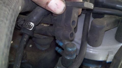 1978 Ford Bronco - A hand manipulates a vacuum line connected to an engine component, likely during a motor rebuild.