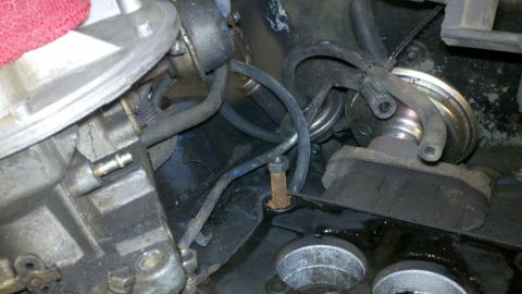1978 Ford Bronco - Close-up view of engine parts, including hoses and a carburetor, with visible oil stains.