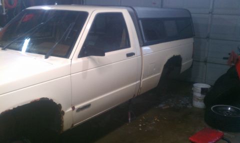 1991 Chevrolet S10 - Side view of a 1991 Chevrolet S10 pickup truck with a camper shell, showing rust damage.