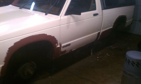 1991 Chevrolet S10 - A white pickup truck is shown from the side, with primer applied to the wheel wells and the front wheel missing.