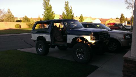 1994 Ford Bronco - Modified Ford Bronco with large tires and lifted suspension sits in a driveway.