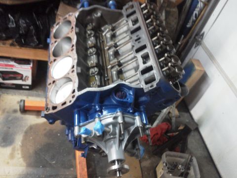 1988 Ford Bronco - A blue engine block with a silver water pump is mounted on an orange engine stand.