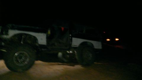 1994 Ford Bronco - A two-tone 1994 Ford Bronco is seen at night with its large tires visible.