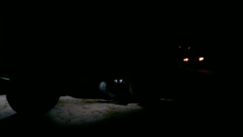 1994 Ford Bronco - Vehicle is barely visible in the dark, with only faint lights showing.