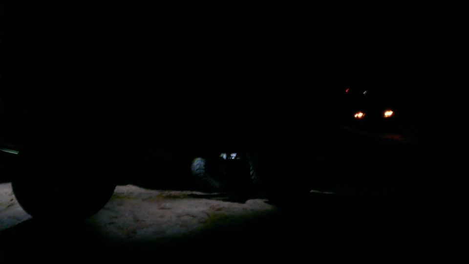 Vehicle parked at night, headlights dimly visible