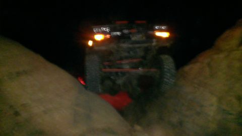 1994 Ford Bronco - The vehicle's taillights are visible as it drives on a dark, unpaved road.