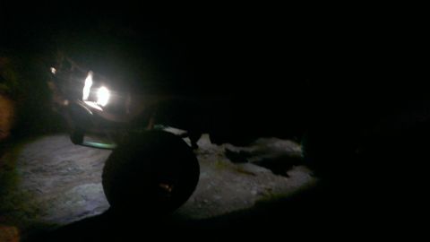 1994 Ford Bronco - A dark vehicle is seen from the side at night, with its headlights illuminating the ground.