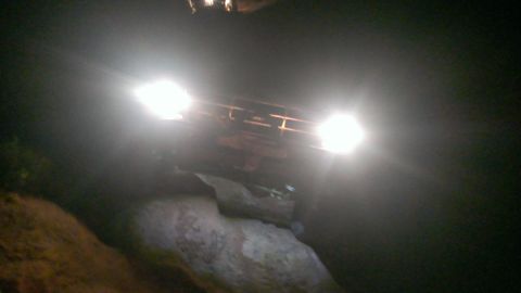 1994 Ford Bronco - Vehicle with headlights on, navigating rocky terrain in the dark.