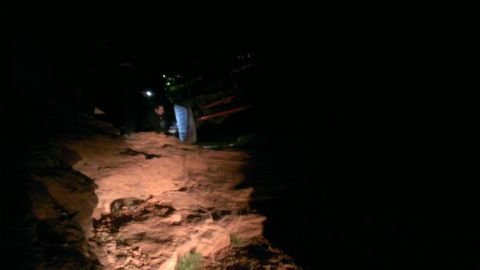 1994 Ford Bronco - A vehicle navigates a rocky path in the dark, illuminated by its headlights.