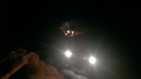 1994 Ford Bronco - A 1994 Ford Bronco is seen at night with its headlights illuminated, partially obscured by darkness and a dirt mound.