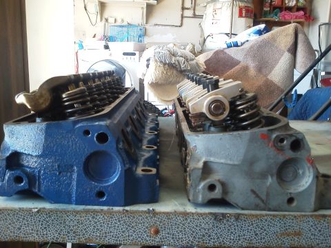 1988 Ford Bronco - A close-up view of two engine cylinder heads, likely for a V8 engine, are displayed in a workshop setting.