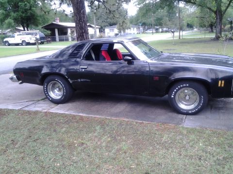 1975 Chevrolet Chevelle - A black 1975 Chevrolet Chevelle coupe is seen from the side, parked on a concrete driveway with a residential background.