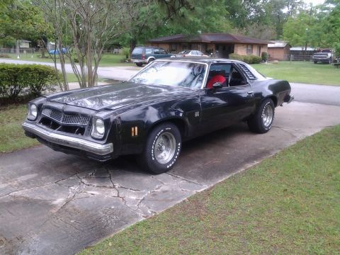 1975 Chevrolet Chevelle - A black coupe with a distinctive grille and louvers on the rear side windows sits on a driveway.