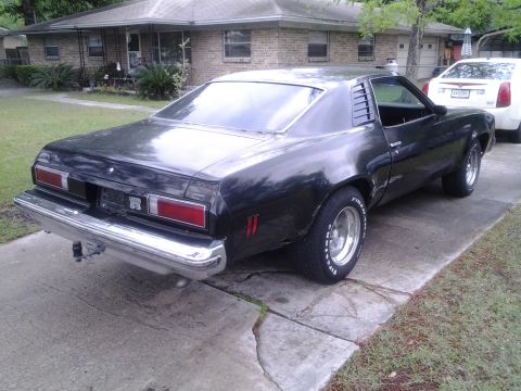 1975 Chevrolet Chevelle - A black 1975 Chevrolet Chevelle coupe is parked on a concrete driveway in front of a brick house.