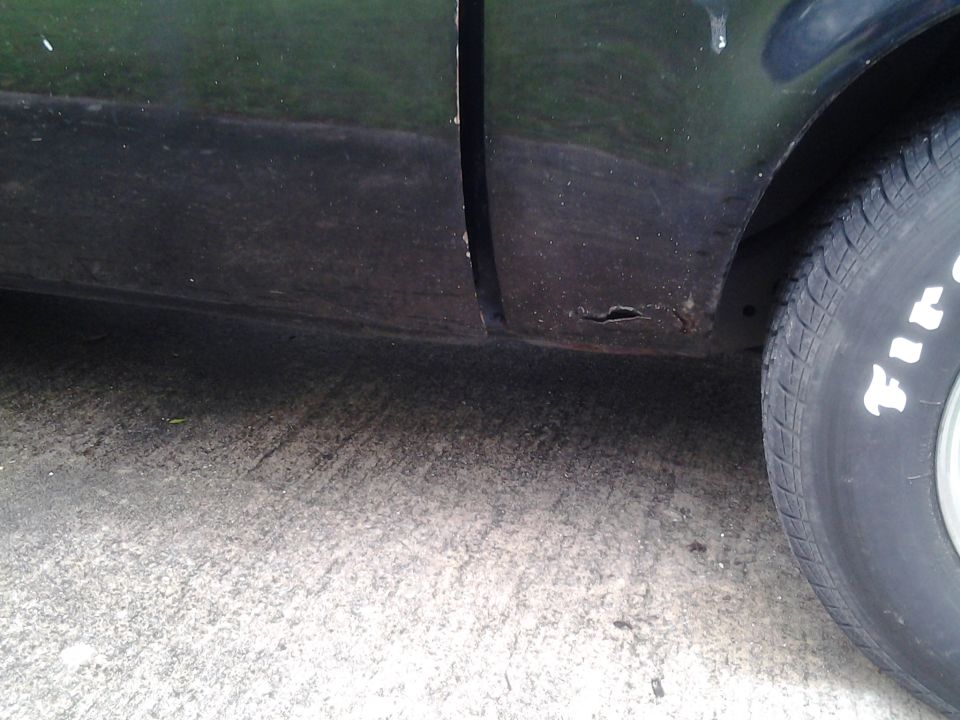 Black car lower body panel with rust and tire. Supermotors.net logo visible