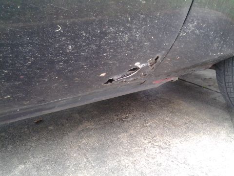 1975 Chevrolet Chevelle - Close-up of a damaged car lower body panel showing significant rust and wear.