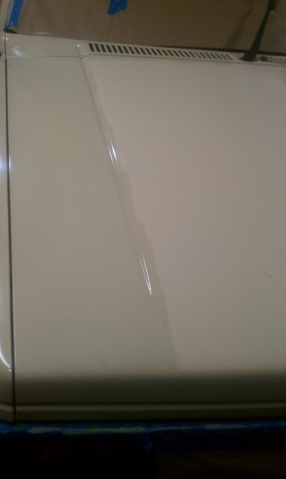 beige vehicle hood and fender with a faint scratch down the middle