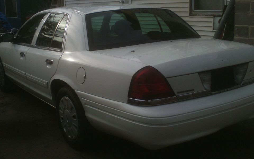 White sedan, rear quarter view, showing chrome trim and taillight
