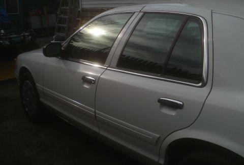 2006 Ford Crown Victoria - This white 2006 Ford Crown Victoria sedan is shown from the side, reflecting the sun.