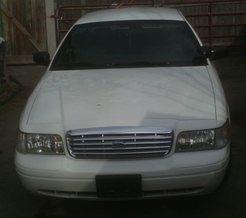 2006 Ford Crown Victoria - The front of a white 2006 Ford Crown Victoria is shown, a chrome grille and clear headlights.