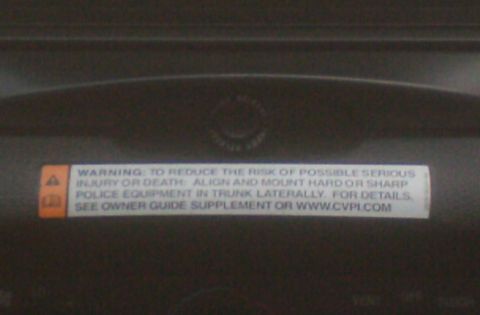 2006 Ford Crown Victoria - A warning label inside the vehicle provides instructions for securing police equipment in the trunk.