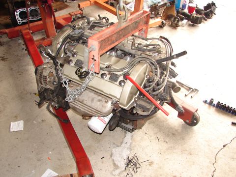 1992 Ford Taurus - Engine assembly being worked on, suspended by a chain hoist on an engine stand.