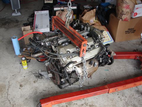 1992 Ford Taurus - Engine assembly being worked on, suspended by a hoist and on an engine stand in a garage.