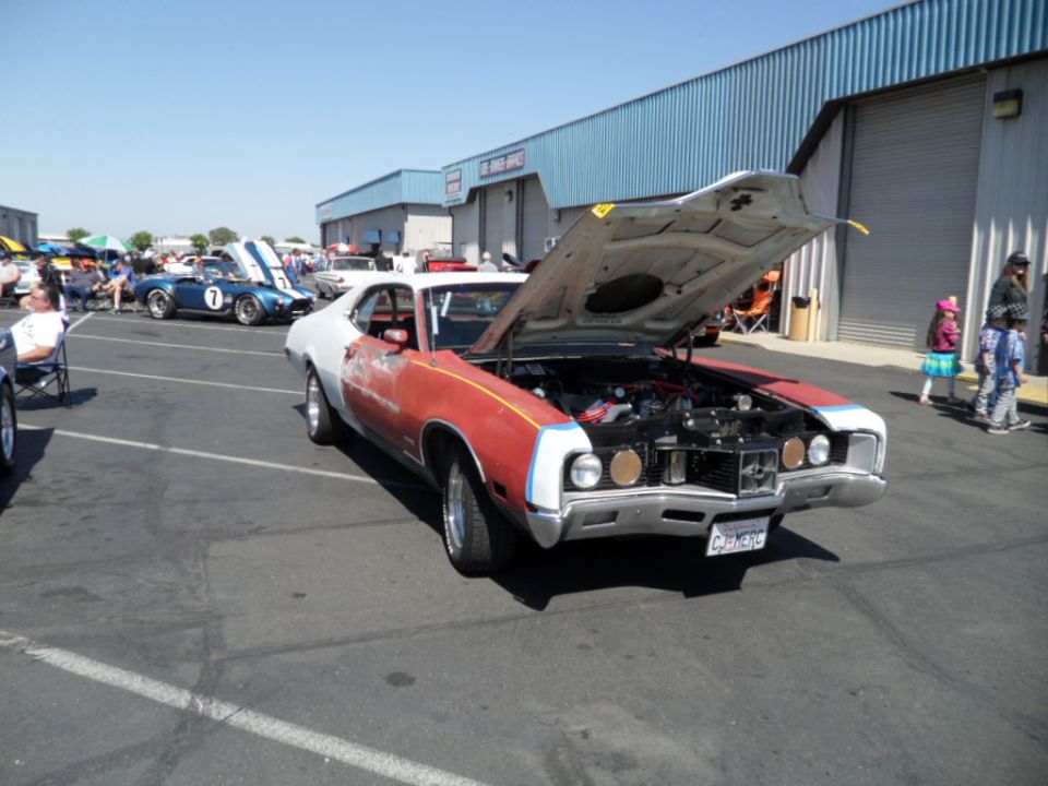 Red and white car with hood open, showing engine. License plate reads CUM296