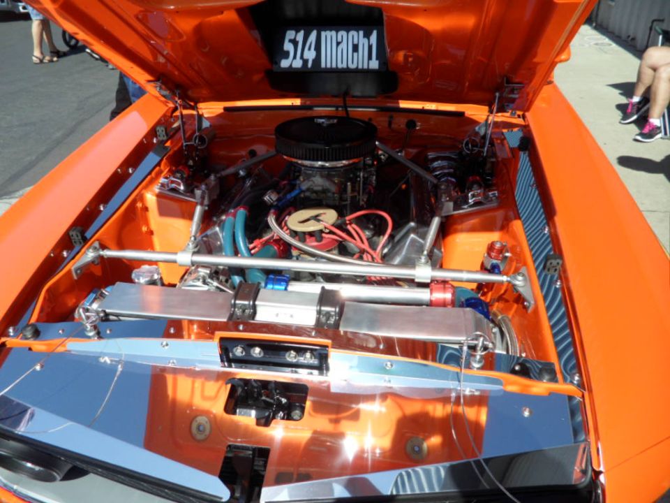 Orange engine bay with "514 mach1" displayed above the engine. Chrome accents and custom hoses are visible