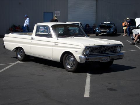 1973 Ford Ranchero - A white pickup truck is parked in a lot with other vehicles and people around.