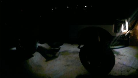1994 Ford Bronco - A close-up view of an SUV's tire and fender is visible in the dark, with a website logo in the corner.