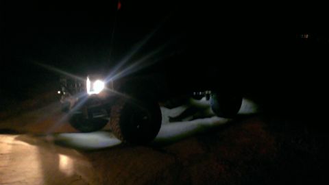 1994 Ford Bronco - Headlights illuminate the front of a dark SUV parked at night.