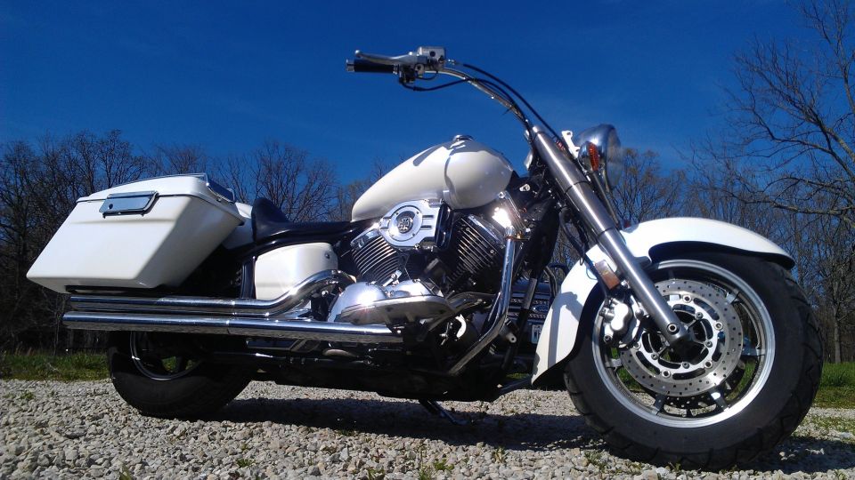 White motorcycle with saddlebags parked on gravel under a clear blue sky