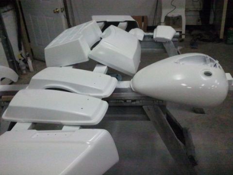 1995 Ford F-150 - Various white fiberglass parts, including a fuel tank and body panels, are arranged on a table in a workshop.
