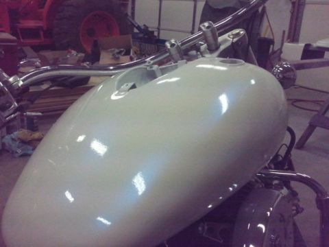1995 Ford F-150 - A close-up view of a motorcycle's white gas tank and handlebars, with a red tractor visible in the background.