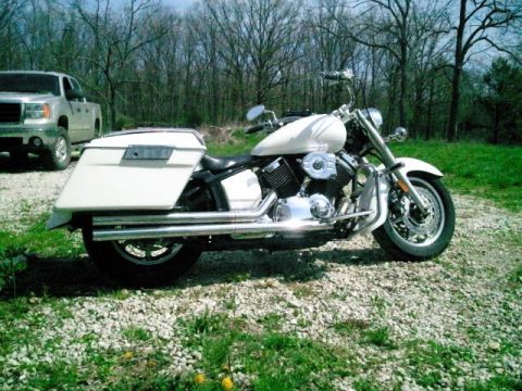 1995 Ford F-150 - A white cruiser motorcycle with large saddlebags is parked on a gravel lot, with a silver pickup truck in the background.