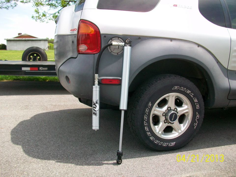Rear quarter panel of a silver SUV with an external Fox shock absorber and fuel filler